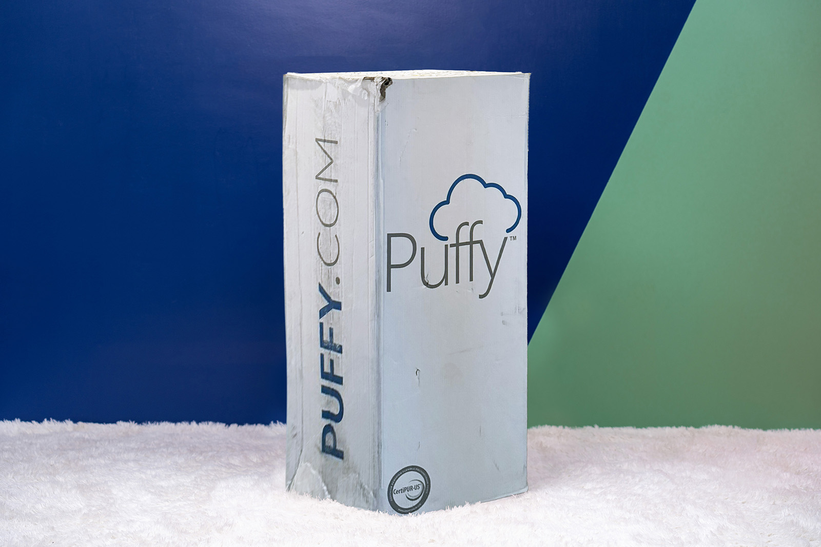 Photo of the Puffy Mattress box standing upright in a bedroom